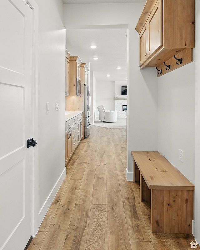 mudroom with baseboards, a fireplace, light wood-style floors, and recessed lighting