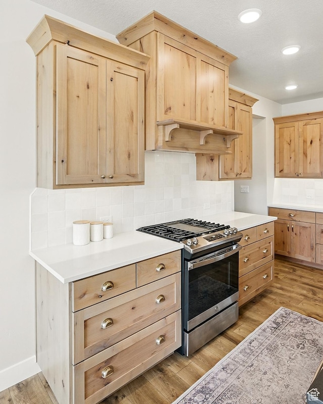 kitchen featuring light brown cabinetry, light wood-type flooring, light countertops, and stainless steel gas range