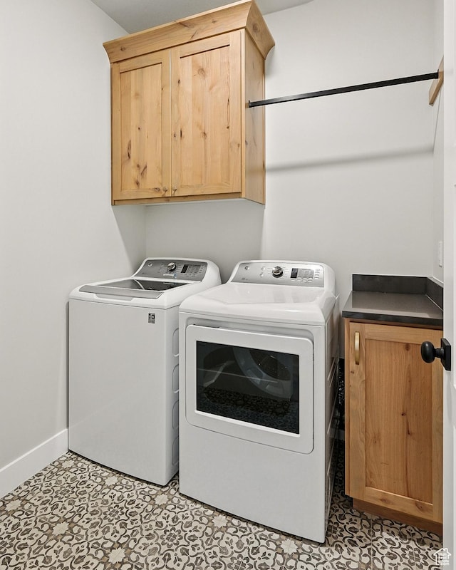 washroom with cabinet space, baseboards, washer and dryer, and light floors