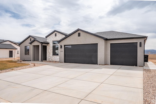 view of front of home with stone siding, driveway, stucco siding, and an attached garage