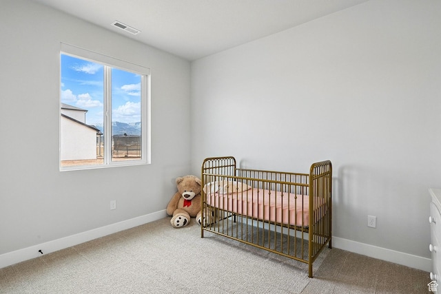 carpeted bedroom with a nursery area, baseboards, and visible vents