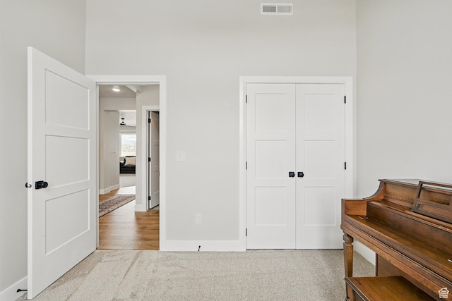 carpeted bedroom with a closet, baseboards, a towering ceiling, and visible vents