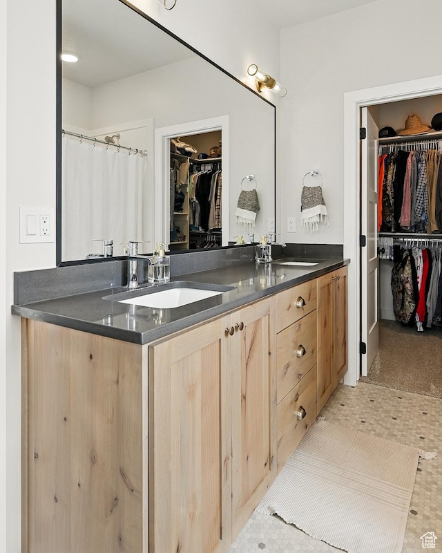 full bath featuring double vanity, a sink, tile patterned flooring, and a spacious closet