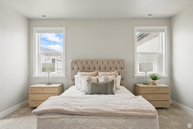 bedroom featuring baseboards, visible vents, multiple windows, and light colored carpet