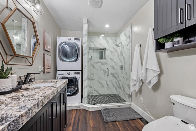 682 N 700 E, Lehi, UT 84043 - bathroom with a textured ceiling, baseboards, wood finished floors, toilet, and stacked washing maching and dryer