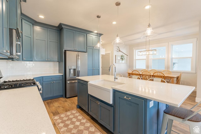 1009 E High Creek Rd, Cove, UT 84320 - kitchen featuring appliances with stainless steel finishes, a sink, a breakfast bar, light wood-style flooring, and recessed lighting