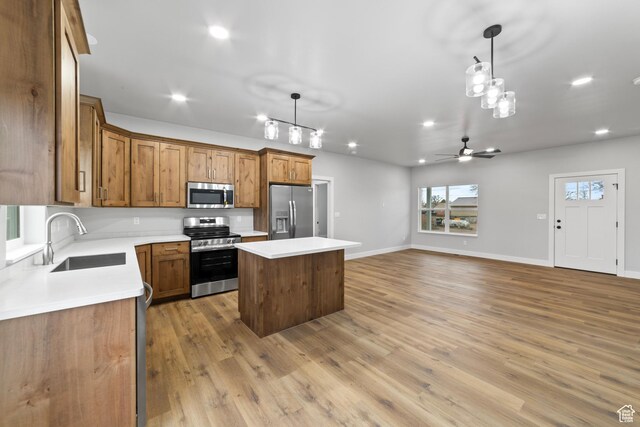 245 E Tidwell Ave Unit 5, Green River, UT 84525 - kitchen featuring a kitchen island, light wood-style floors, brown cabinetry, appliances with stainless steel finishes, and a sink