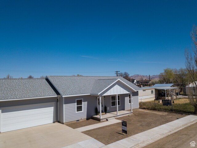 245 E Tidwell Ave Unit 5, Green River, UT 84525 - view of front facade featuring board and batten siding, covered porch, an attached garage, a shingled roof, and concrete driveway