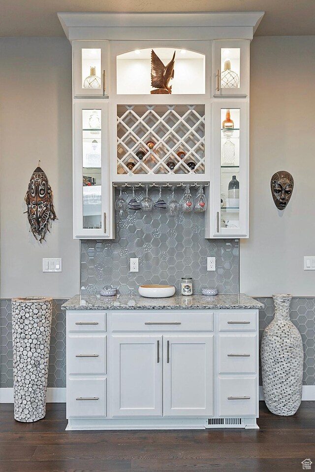 bar with backsplash, wet bar, and dark wood-style flooring