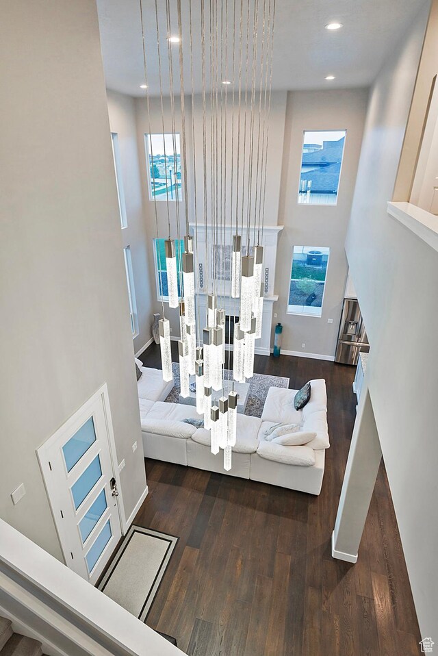 interior space featuring stairs, wood finished floors, baseboards, a towering ceiling, and recessed lighting