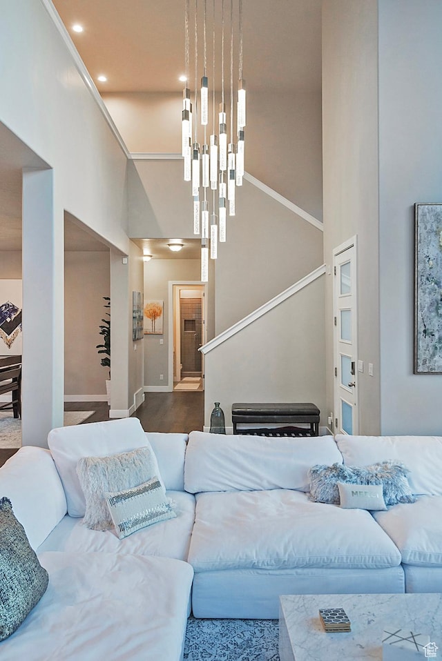 living room with baseboards, stairs, recessed lighting, a high ceiling, and a notable chandelier