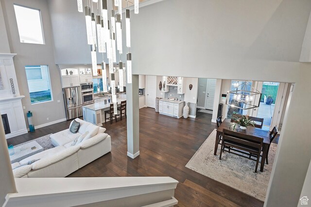 living room with baseboards, dark wood-style floors, a high ceiling, and a chandelier