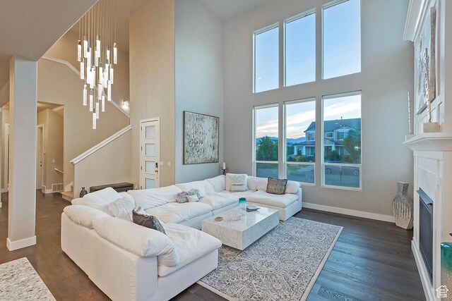 living area with baseboards, dark wood-style flooring, a fireplace, and stairway