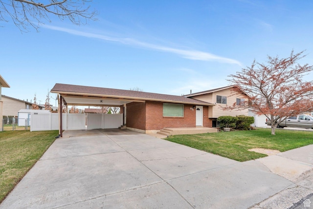 tri-level home with fence, a front yard, brick siding, driveway, and a carport