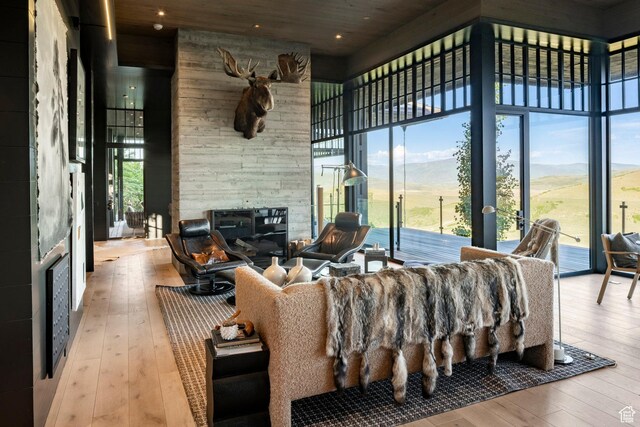 8006 N Sunrise Loop, Park City, UT 84098 - living area featuring hardwood / wood-style flooring, a stone fireplace, a towering ceiling, a mountain view, and expansive windows