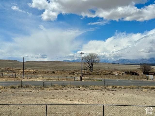 view of yard featuring a mountain view, fence, and a rural view
