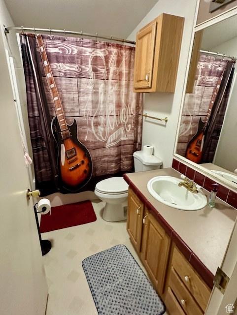 bathroom featuring toilet, a shower with shower curtain, and vanity