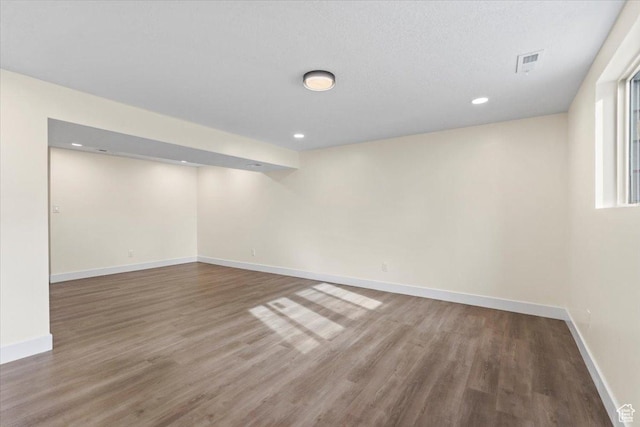 below grade area with baseboards, visible vents, wood finished floors, and recessed lighting