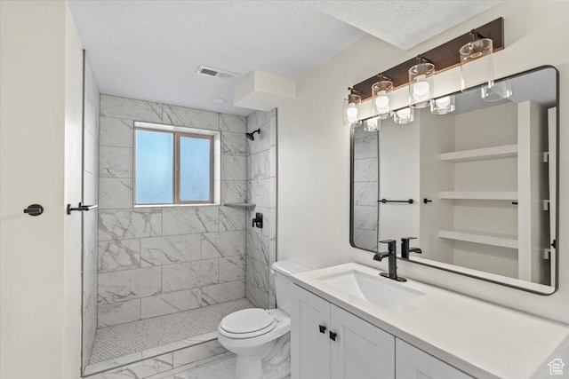 full bathroom featuring vanity, toilet, marble finish floor, visible vents, and tiled shower