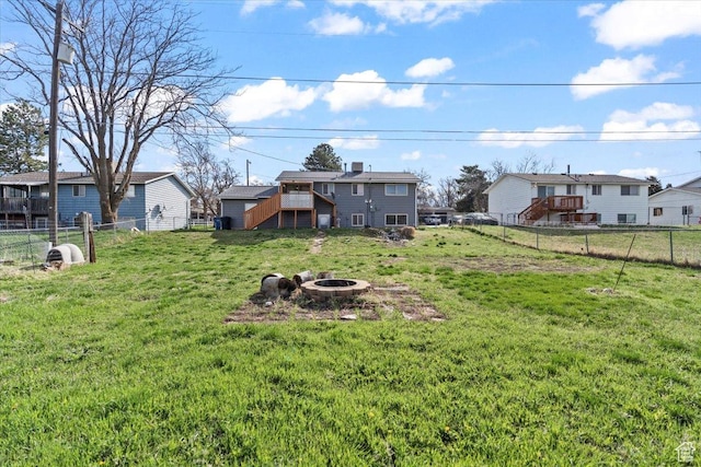 view of yard featuring an outdoor fire pit, a fenced backyard, stairway, and a residential view