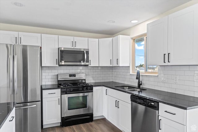 kitchen with dark stone countertops, dark wood-style floors, a sink, and stainless steel appliances