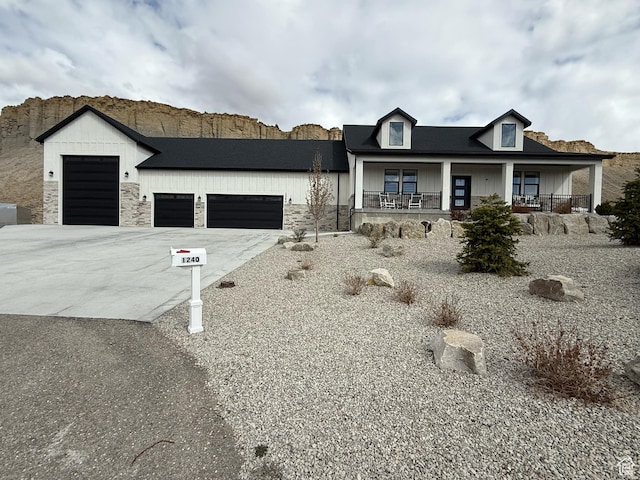 view of front of house featuring stone siding, a porch, an attached garage, and concrete driveway