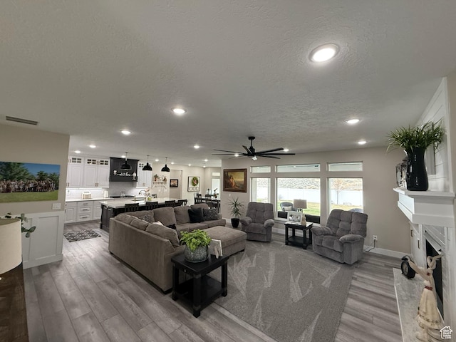 1240 W 2360 N, Helper, UT 84526 - living room featuring a premium fireplace, a textured ceiling, visible vents, a ceiling fan, and wood finished floors