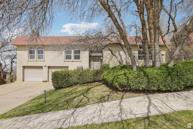 bi-level home featuring brick siding, driveway, an attached garage, and a front lawn