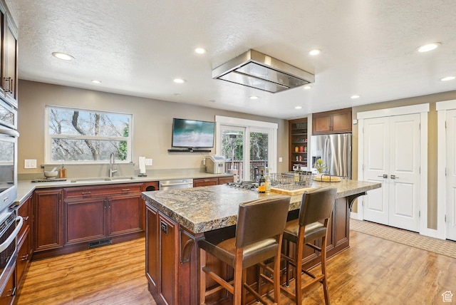 1349 E Madera Hills Dr S, Bountiful, UT 84010 - kitchen featuring light wood-type flooring, a kitchen island, a kitchen bar, appliances with stainless steel finishes, and a sink