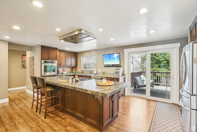 1349 E Madera Hills Dr S, Bountiful, UT 84010 - kitchen featuring appliances with stainless steel finishes, a kitchen breakfast bar, a kitchen island with sink, and light wood-style floors