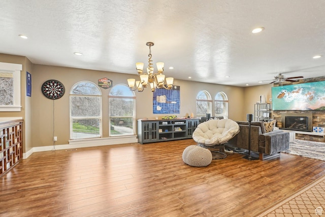 1349 E Madera Hills Dr S, Bountiful, UT 84010 - living area featuring a stone fireplace, a textured ceiling, recessed lighting, wood finished floors, and ceiling fan with notable chandelier