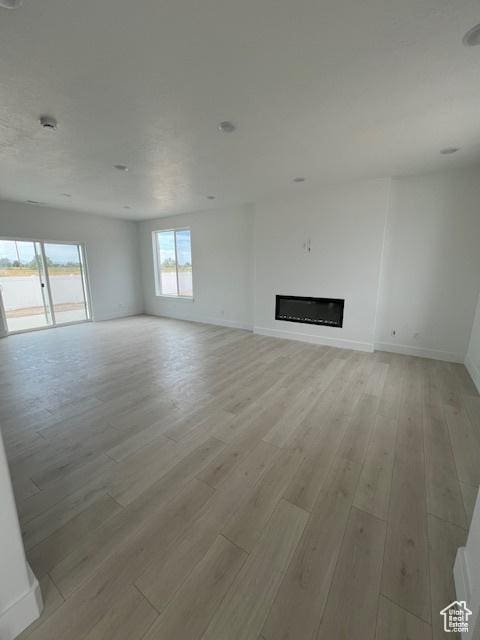 3199 N 3500 W Unit 379, Plain City, UT 84404 - unfurnished living room with light wood-style flooring and a glass covered fireplace