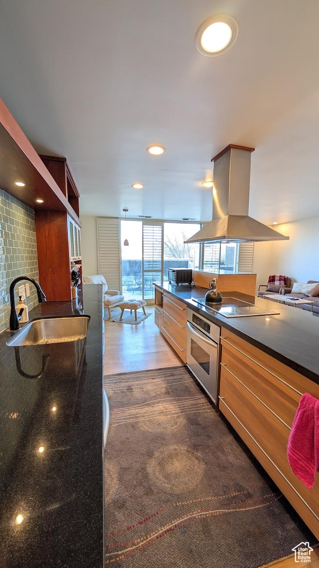 777 E S Temple Unit 3J, Salt Lake City, UT 84102 - kitchen with dark countertops, a sink, stainless steel oven, island range hood, and dark wood-type flooring