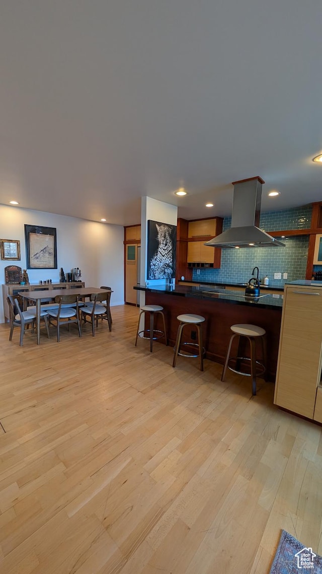 777 E S Temple Unit 3J, Salt Lake City, UT 84102 - kitchen with light wood-style floors, backsplash, island range hood, and dark countertops