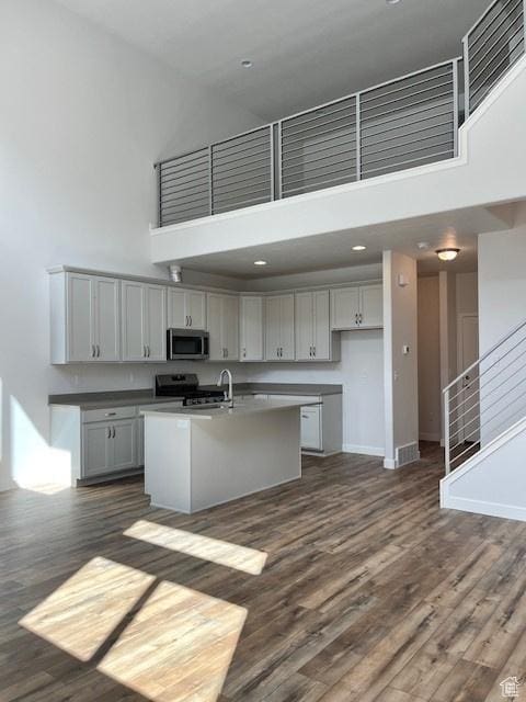 6850 S Static Peak Dr Unit 261, West Jordan, UT 84081 - kitchen with baseboards, dark wood finished floors, a towering ceiling, stainless steel appliances, and a kitchen island with sink