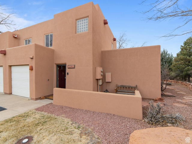3245 E Fairway Loop, Moab, UT 84532 - pueblo revival-style home featuring a garage, driveway, and stucco siding