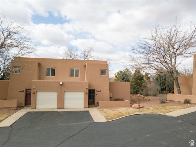 3245 E Fairway Loop, Moab, UT 84532 - pueblo-style house with a garage, driveway, and stucco siding
