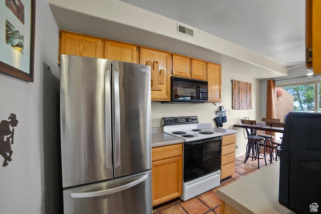 3245 E Fairway Loop, Moab, UT 84532 - kitchen with black microwave, light tile patterned floors, light countertops, electric range, and freestanding refrigerator