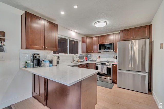 5518 S 875 E, South Ogden, UT 84405 - kitchen featuring a sink, light wood finished floors, tasteful backsplash, appliances with stainless steel finishes, and a peninsula