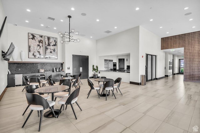 dining room featuring baseboards, a towering ceiling, and visible vents