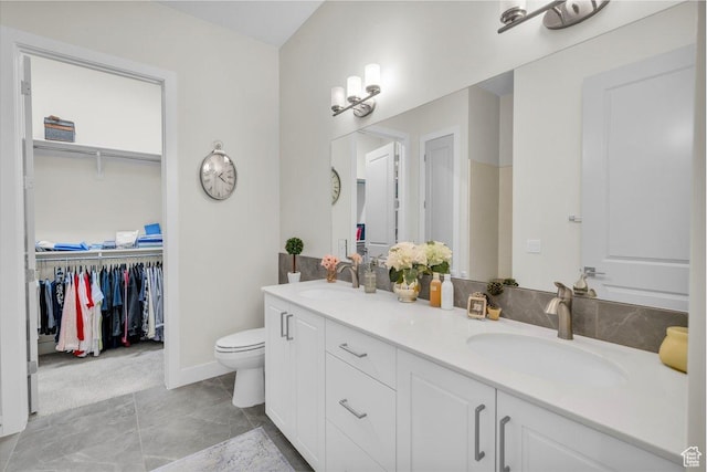 bathroom featuring double vanity, a sink, and a spacious closet