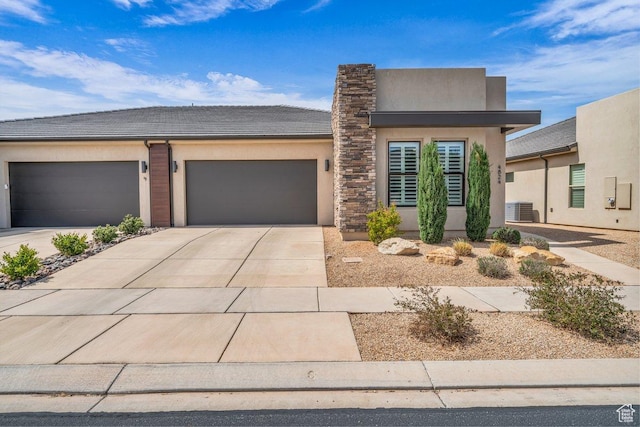 view of front of home with central AC unit, an attached garage, concrete driveway, a tile roof, and stucco siding