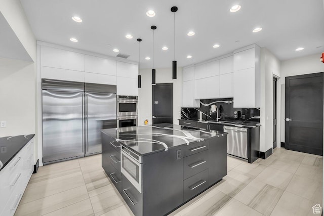 kitchen featuring modern cabinets, dark countertops, visible vents, and appliances with stainless steel finishes