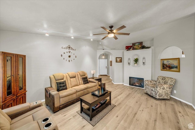 544 S Fiesta Dr, Ivins, UT 84738 - living room featuring baseboards, arched walkways, light wood-style floors, a ceiling fan, and a glass covered fireplace