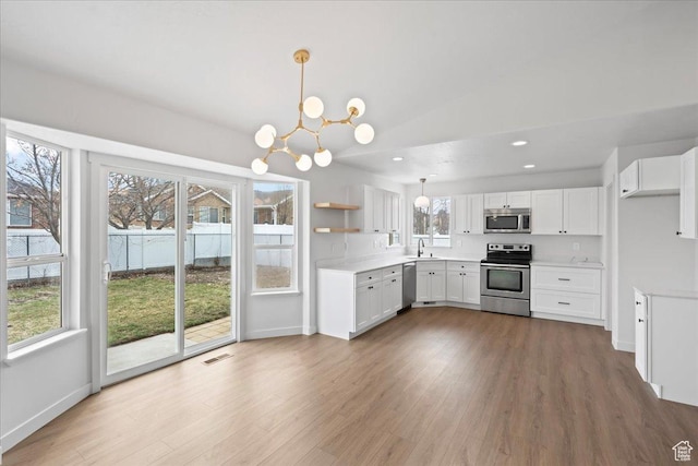 4489 W Black Elk Way, West Jordan, UT 84088 - kitchen with an inviting chandelier, visible vents, white cabinets, appliances with stainless steel finishes, and wood finished floors