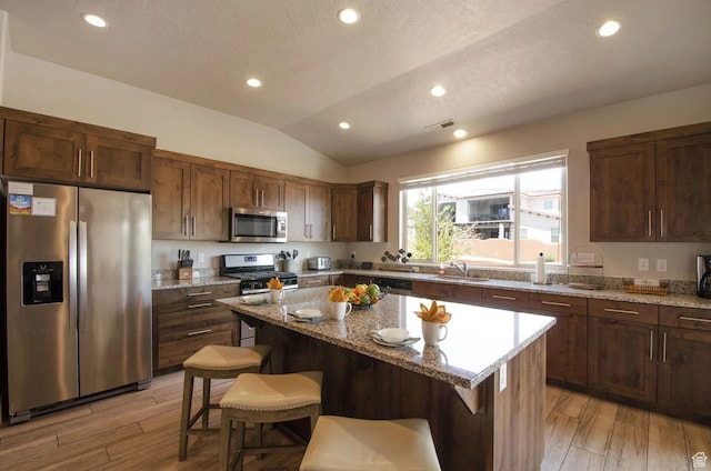 3823 W Dream Cir Unit 120, Santa Clara, UT 84765 - kitchen with a kitchen island, appliances with stainless steel finishes, lofted ceiling, a sink, and a breakfast bar area