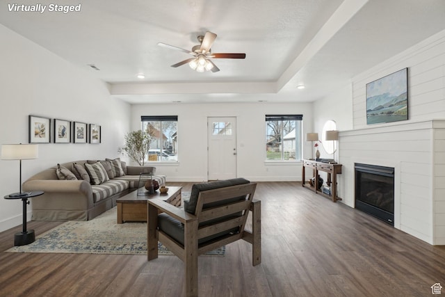 living area featuring a glass covered fireplace, baseboards, recessed lighting, ceiling fan, and wood finished floors