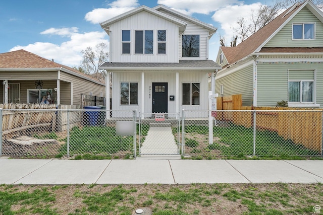 view of front of house with board and batten siding, a front lawn, a fenced front yard, a porch, and a gate