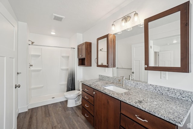 bathroom featuring vanity, toilet, a shower stall, visible vents, and wood finished floors