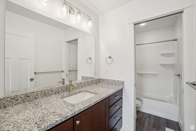 bathroom featuring toilet, vanity, wood finished floors, and  shower combination